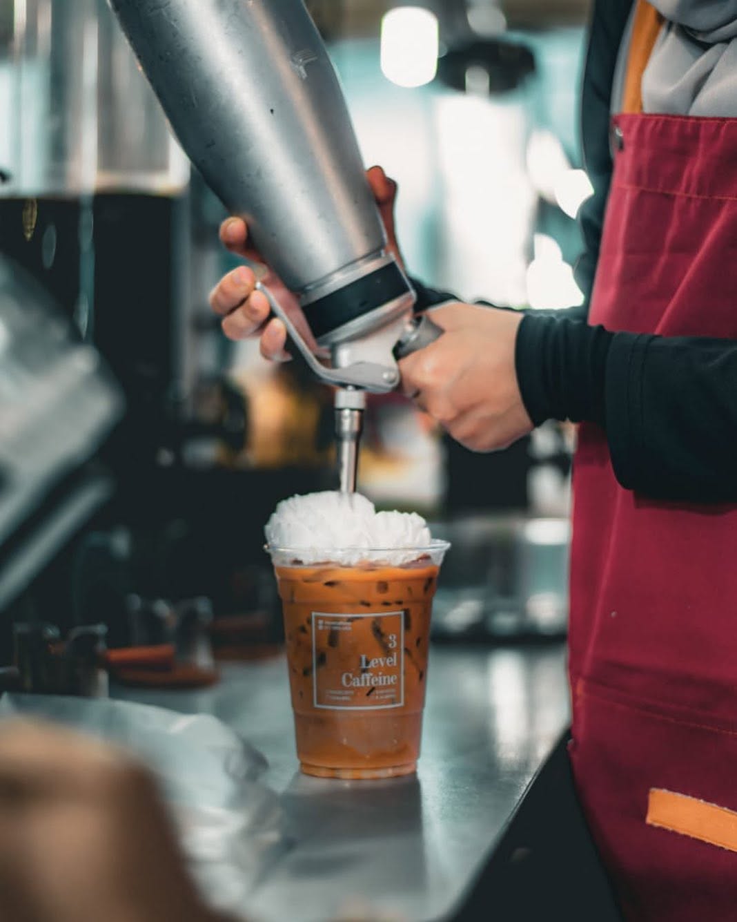 Barister topping an iced coffee with whipped cream